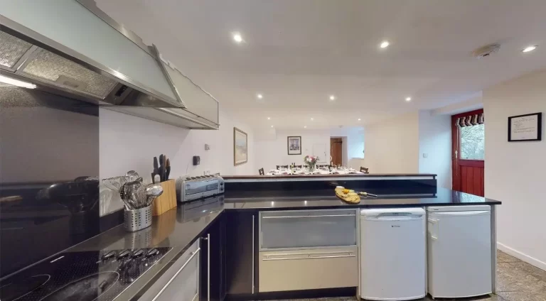 Modern fitted kitchen at Toft Barn, Toft Estate, featuring contemporary appliances and traditional wooden ceiling beams.